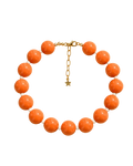 A beaded necklace with large round orange-brown beads separated by small white beads, with a gold chain clasp and star charm, displayed on a beige background with leaf shadows. Text above and below reads 'STACKED BY VALE' and 'CAPRI POP NECKLACE'.