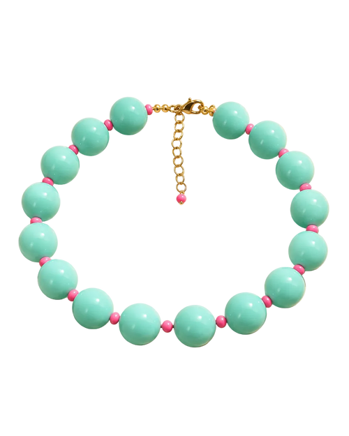 A beaded necklace with large mint green beads and small pink spacer beads, displayed on a beige background with decorative shadows. The necklace is labeled 'MIAMI POP NECKLACE' and 'SUMMER HEIRLOOMS' by the brand 'STACKED BY VALE'.
