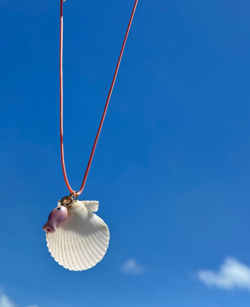 Necklace with a shell pendant against a blue sky